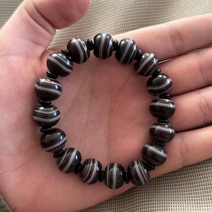 Op de afbeelding: Een armband van zwart-wit gestreepte agaat met zwarte spacers.