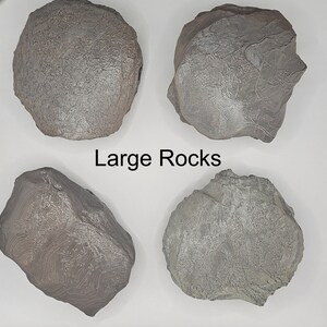 Puede incluir: Cuatro rocas grandes de color gris con un patrón blanco veteado. Las rocas están dispuestas en forma de cuadrado sobre un fondo blanco. El texto "Large Rocks" está escrito en negro debajo de las rocas.