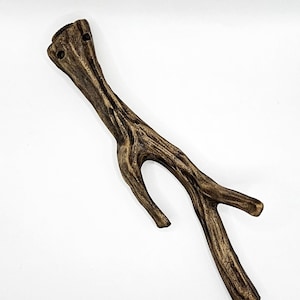 May include: A brown, wooden, decorative branch with a forked end. The branch has a rough, textured surface and appears to be made of natural wood.