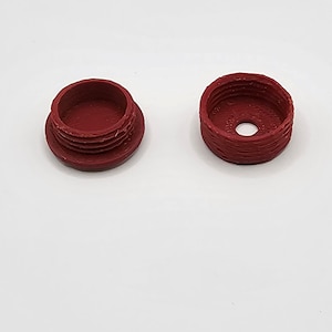 May include: Two red plastic caps, one with a hole in the centre and the other with a smooth surface.