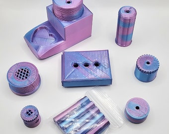 May include: A collection of 3D-printed accessories in shades of blue, purple, and pink. The set includes a box with holes, a cylindrical piece, a heart-shaped tray, and several other components. The items are arranged on a white surface.