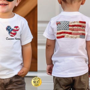 May include: A white short-sleeve t-shirt featuring a small Mickey Mouse-shaped American flag patch on the front left chest with the text Custom Name below it, and a large rectangular American flag patch on the back made of various fabric patterns.
