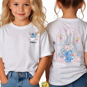 May include: White t-shirt featuring a cartoon Stitch design. The front of the shirt shows Stitch in a teacup with the name "Isabella". The back of the shirt displays a castle scene with Stitch, balloons, and fireworks.