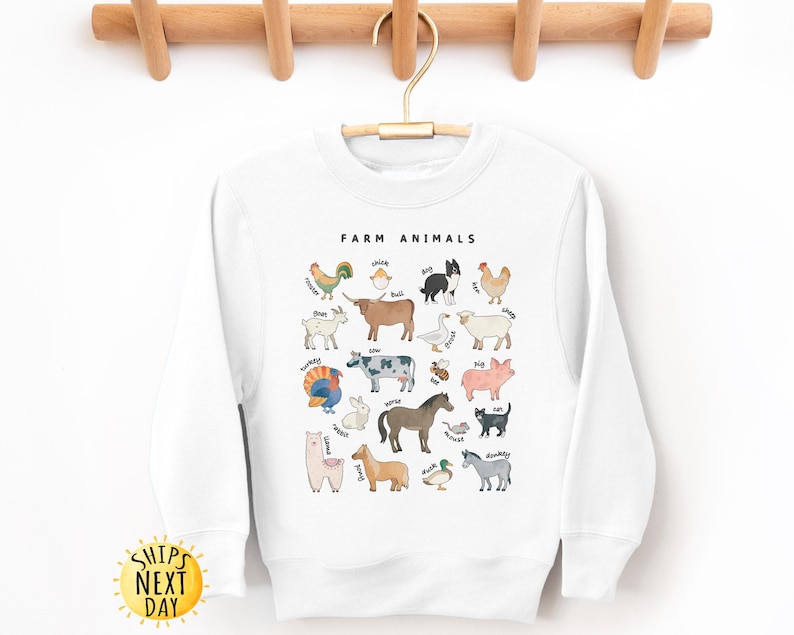 K&ouml;nnte beinhalten: Wei&szlig;er Pullover mit einer Grafik von Nutztieren und ihren Namen. Der Text "Farm Animals" befindet sich oben auf der Grafik.