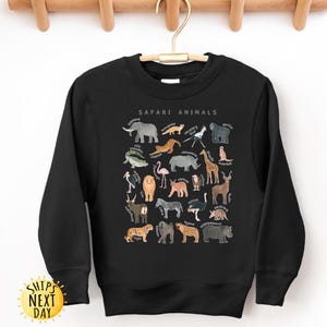 May include: Black sweatshirt with a graphic print of safari animals. The print includes a variety of animals such as a lion, elephant, giraffe, zebra, and more. The text "Safari Animals" is printed above the graphic.