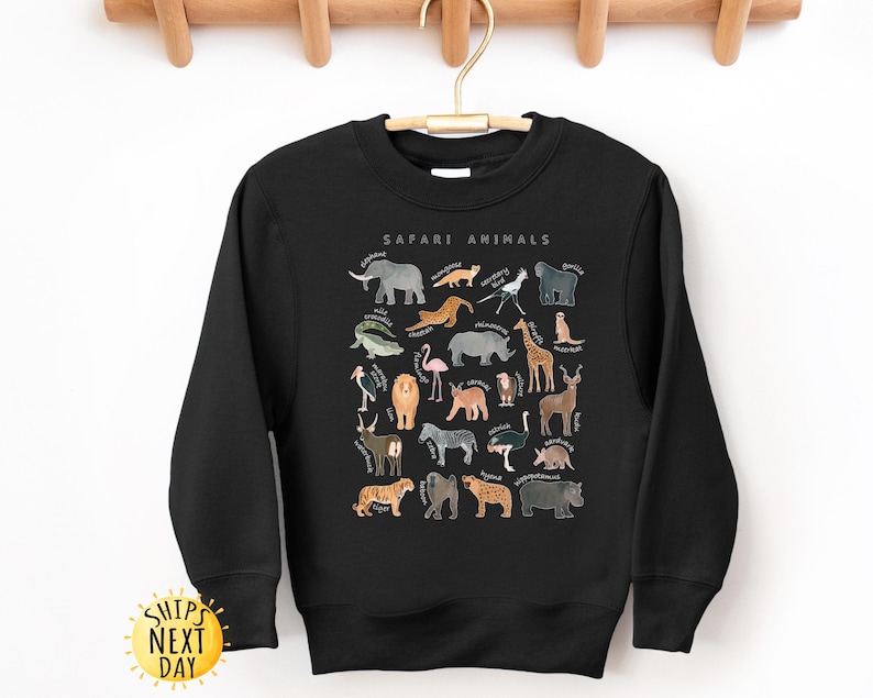 May include: Black sweatshirt with a graphic print of safari animals. The print includes a variety of animals such as a lion, elephant, giraffe, zebra, and more. The text "Safari Animals" is printed above the graphic.
