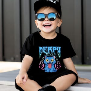 May include: Black t-shirt featuring the word "DERPY" in blue, and a cartoon blue cat with its tongue out, surrounded by pink and purple flames. The child is wearing a black cap and sunglasses.