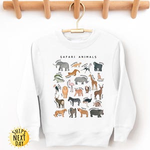 May include: White sweatshirt with a graphic of safari animals, including a giraffe, elephant, lion, zebra, and more. The text "SAFARI ANIMALS" is printed above the graphic.