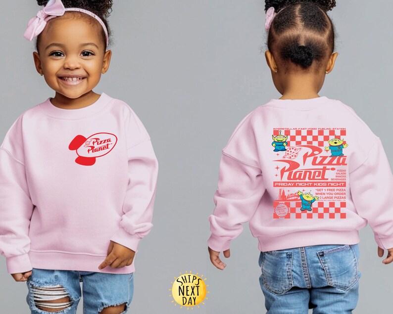 Puede incluir: Sudadera rosa claro con el logo de Pizza Planet en rojo en la parte delantera. La parte trasera de la sudadera tiene un dise&ntilde;o m&aacute;s grande con el logo de Pizza Planet, personajes alien&iacute;genas y texto sobre un fondo a cuadros rojos y blancos.