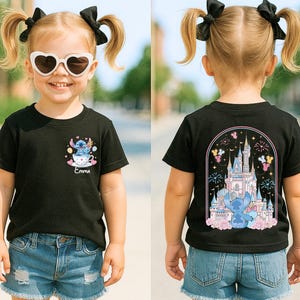 May include: Black t-shirt with a cartoon graphic of a blue alien in a teacup on the front and a castle design on the back. The shirt is worn by a young child with blonde pigtails and heart-shaped sunglasses.