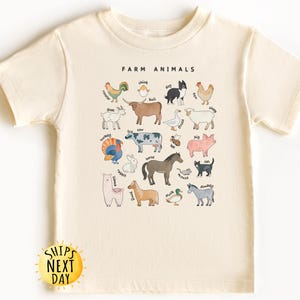 K&ouml;nnte beinhalten: Ein cremefarbenes T-Shirt mit einer Grafik von Nutztieren und ihren Namen. Der Text "FARM ANIMALS" ist oben auf der Grafik in Schwarz gedruckt.