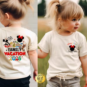 May include: Two children wearing cream-colored t-shirts with Disney-themed graphics. One shirt features "Family Vacation *2026*" and Disney characters on the back. The other shirt has a Minnie Mouse design and "Disney 2026" with a space for a custom name.