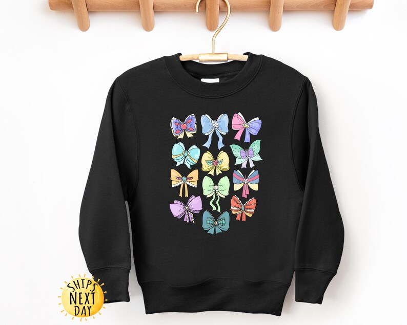 May include: Black sweatshirt with a colorful graphic of bows. The bows are in various colors and designs, including pink, blue, yellow, and green.