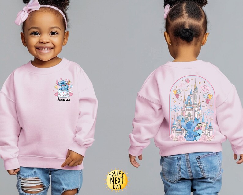 May include: A light pink sweatshirt featuring a cartoon Stitch design. The front shows Stitch in a teacup with the name "Isabella". The back displays a castle scene with Stitch. The sweatshirt is worn by a young child.