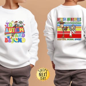 K&ouml;nnte beinhalten: Wei&szlig;es Sweatshirt mit farbenfrohen Grafiken und Text. Auf der Vorderseite steht "TO AUTISM AND BEYOND" mit Toy Story-Charakteren. Auf der R&uuml;ckseite steht "AUTISM AWARENESS And Beyond" mit Woody und Buzz Lightyear und den Worten "ACCEPTANCE, INCLUSION, ADVOCACY".