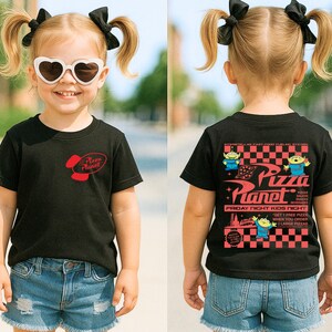 Puede incluir: Una camiseta negra con el logo rojo de "Pizza Planet" en la parte delantera y un gr&aacute;fico en la parte trasera. El gr&aacute;fico incluye el texto "Pizza Planet" e im&aacute;genes de extraterrestres. El ni&ntilde;o lleva gafas de sol en forma de coraz&oacute;n y pantalones cortos vaqueros.