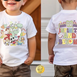 May include: White t-shirt featuring a colourful cartoon image of Toy Story characters on the front and the text "To Infinity and Beyond" on the back.