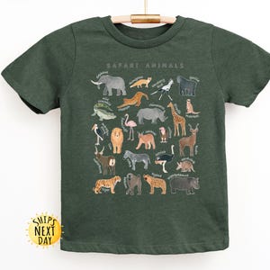 May include: A dark green t-shirt with a print of safari animals. The print includes a variety of animals, including a lion, elephant, giraffe, zebra, and ostrich. The text "Safari Animals" is printed at the top of the design.