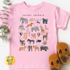 May include: Pink t-shirt with a graphic of safari animals and their names. The shirt has the text "SAFARI ANIMALS" at the top.