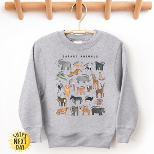 May include: A gray sweatshirt with a graphic print of safari animals. The text "SAFARI ANIMALS" is printed in black at the top of the graphic.