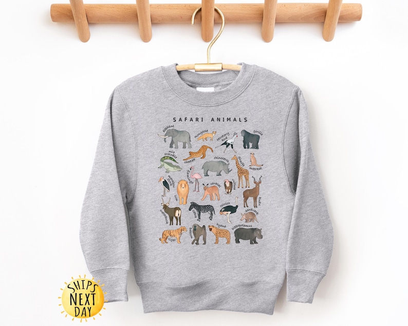 May include: A gray sweatshirt with a graphic print of safari animals. The text "SAFARI ANIMALS" is printed in black at the top of the graphic.