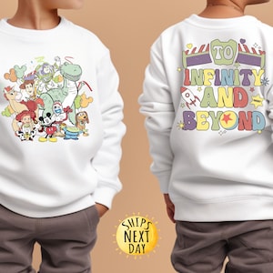 May include: White sweatshirt with a colourful graphic of Toy Story characters on the front and the text "To Infinity and Beyond" on the back.