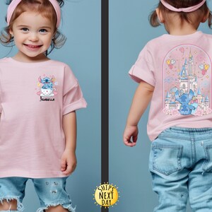 May include: Pink t-shirt featuring a cartoon Stitch design on the front and back. The front design shows Stitch in a teacup with the name "Isabella". The back design features Stitch in front of a castle with fireworks and balloons.