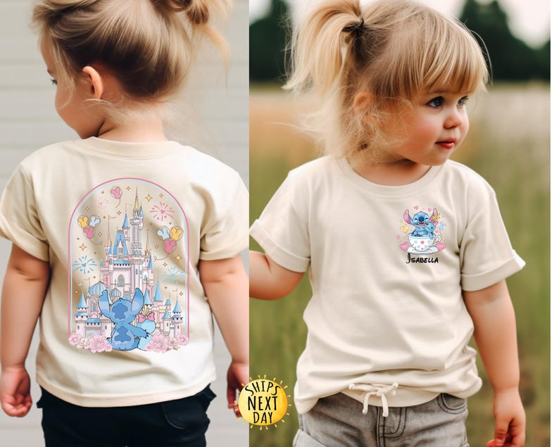 May include: Two cream-colored t-shirts featuring a cartoon character design. One shirt has a castle and character graphic on the back. The other shirt has a character graphic and the name "Isabella" on the front. Both shirts have rolled-up sleeves.