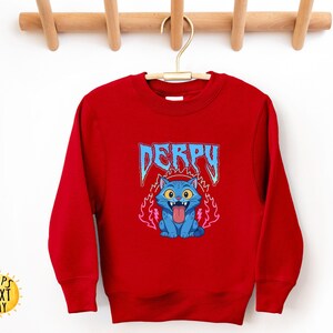 May include: A red sweatshirt with a blue cartoon cat graphic, tongue out and surrounded by flames. The word "DERPY" is above the cat in a blue, stylized font. The sweatshirt has a crew neck and long sleeves.