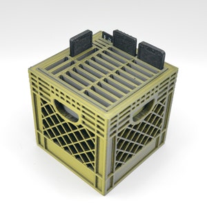 May include: A yellow plastic crate with a grid pattern and four black rectangular objects inside. The crate has a handle on the side.