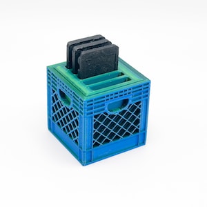 May include: A blue and green plastic crate with a black plastic insert for holding small items. The crate has a handle on the side.
