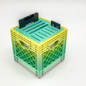 May include: A green, yellow, and pink plastic crate with a built-in organizer for memory cards. The crate has a label that says "Lexar" on it.