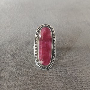Peut inclure: Une bague en argent avec une grande pierre précieuse rouge de forme ovale sertie dans une bélière à perles.