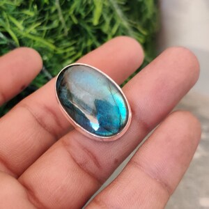 Könnte beinhalten: Ein silberner Ring mit einem großen ovalen, blauen Labradorit-Edelstein. Der Stein hat einen schillernden Glanz.