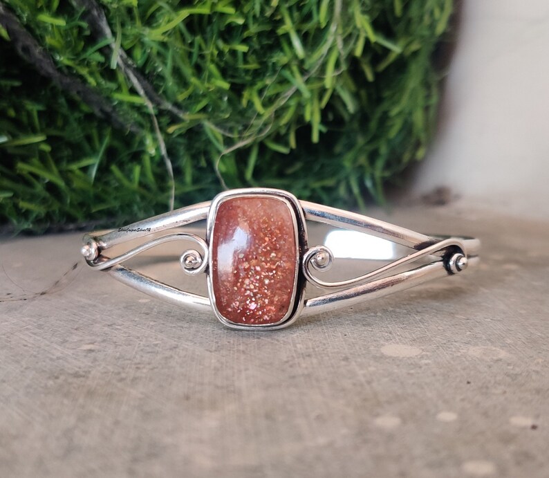May include: Silver bracelet with a rectangular sunstone gemstone. The bracelet has a delicate, twisted design.