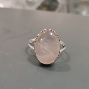 May include: A silver ring featuring a large oval rose quartz gemstone.