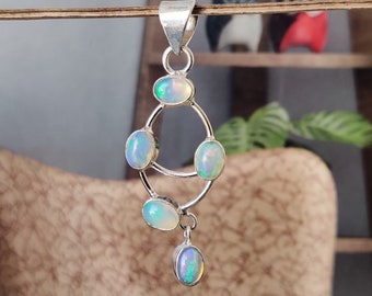 May include: A silver pendant featuring five iridescent opal stones. The stones are set in a delicate, curved design. The pendant is ideal for adding a touch of elegance to any outfit.