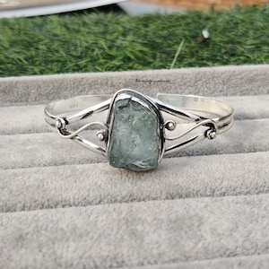 Peut inclure: Un bracelet en argent avec une pierre précieuse aquamarine bleu clair. Le bracelet a un design délicat et torsadé.