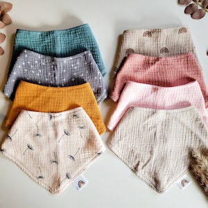 Puede incluir: Conjunto de diez baberos de muselina para bebé con diferentes patrones. Los baberos son de varios colores, incluyendo azul verdoso, gris, amarillo mostaza, rosa y beige. Algunos de los patrones incluyen una cruz, un arcoíris y dientes de león.