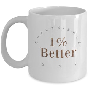 May include: White ceramic mug with a curved handle. The mug features the text "1% Better Day" in a brown, wood-like font, surrounded by the words "Every Single" in a circular arrangement.
