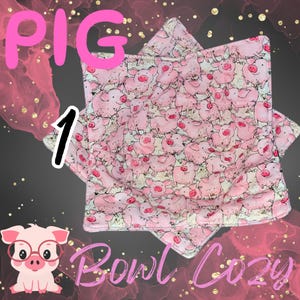 May include: Pink bowl cozy with a pattern of cartoon pigs. The word "PIG" is written in pink, and the number "1" is written in black. The words "Bowl Cozy" are written in pink at the bottom of the image.
