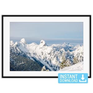 Peut inclure: Une impression encadrée représentant une chaîne de montagnes enneigées sous un ciel bleu pâle. Les sommets sont déchiquetés et couverts de neige, avec des arbres à feuilles persistantes sur les pentes inférieures. Le texte "INSTANT DOWNLOAD" est dans un encadré bleu.