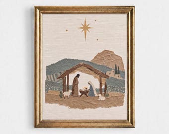 Peut inclure: Une impression d'art encadrée représentant un collage en papier déchiré d'une scène de nativité. L'œuvre montre des personnages dans une étable avec une étoile dorée au-dessus, sur un paysage de collines bleues et de sol beige, dans un cadre doré.