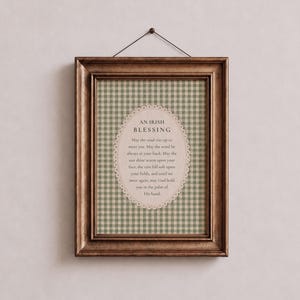 May include: A rectangular wall frame with a dark wood finish containing a print with a green and white gingham background. An oval cream-colored label in the center features the text AN IRISH BLESSING followed by the traditional poem in black.
