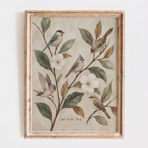 Op de afbeelding: Een ingelijste kunstdruk met vier kleine vogels op takken met groene bladeren en witte bloemen. De vogels zijn afgebeeld in tinten bruin, grijs en wit. De tekst "Look at the Birds" staat in het onderste centrale gedeelte van de afbeelding.