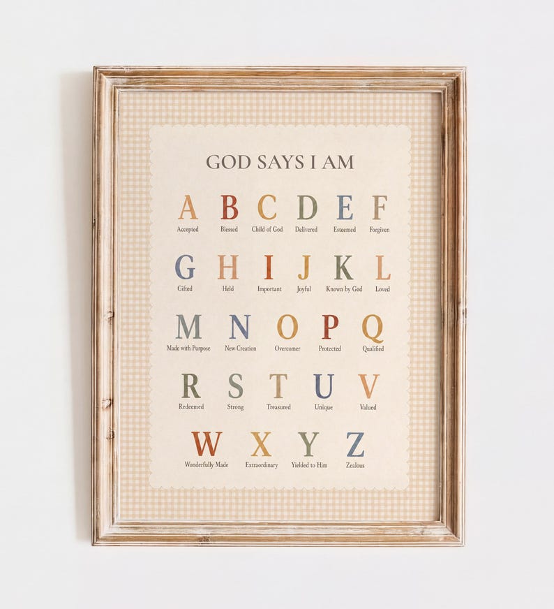 May include: A framed wall art print featuring the alphabet from A to Z in a muted color palette. Each letter is paired with a corresponding word, starting with the title GOD SAYS I AM at the top. The print has a beige background with a subtle gingham border, all encased in a light brown wooden frame.
