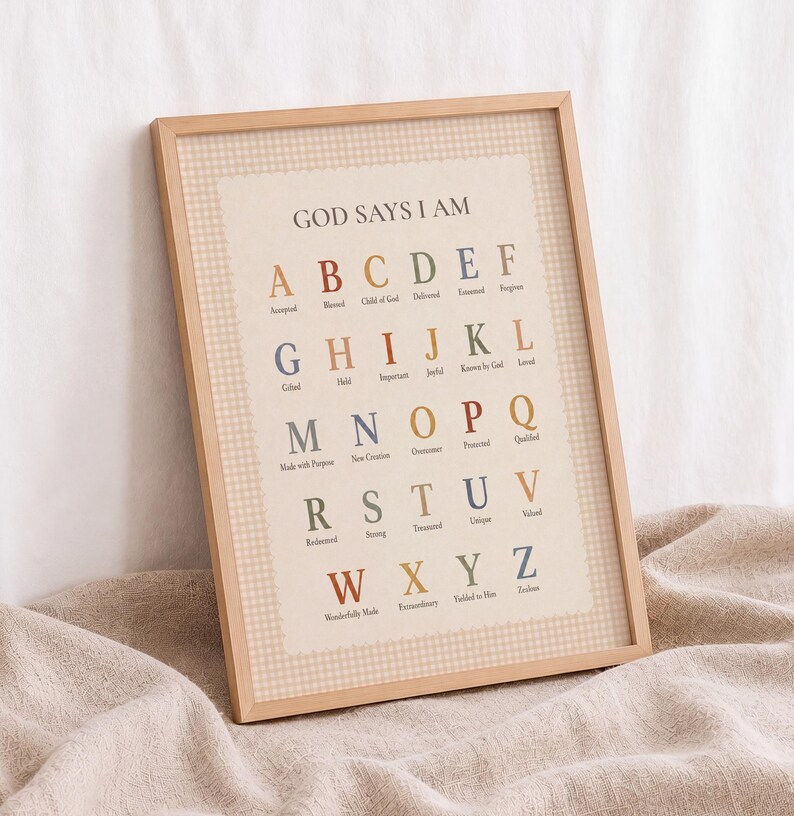 May include: A framed wall art print featuring the text GOD SAYS I AM followed by the alphabet from A to Z. Each letter is paired with a descriptive word in a muted color palette. The print has a light beige background with a subtle gingham border.