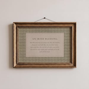 May include: A framed print featuring the text "AN IRISH BLESSING." The print has a gold-colored frame and a background of green and white checkered pattern. The text is centered on a beige background with a decorative lace border.