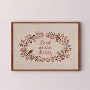 May include: Cross-stitch picture in a wooden frame. The design shows a floral wreath with four birds and the text "Look at the Birds." The embroidery uses various colours, including red, blue, and green, on a beige background.