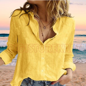 a woman standing on a beach wearing a yellow shirt